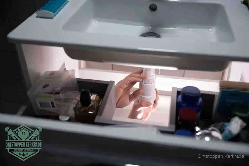 Een pompfles met zeep boven een wastafel, de heet water en afwasmiddel-methode om een vetprop in de afvoer los te maken in Kerkrade