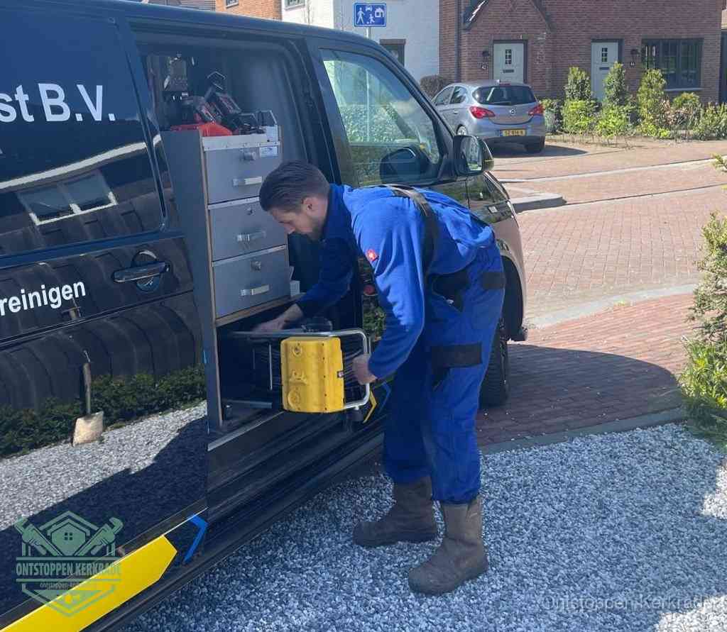 Een monteur pakt buiten op de oprit gereedschap uit de bedrijfsbus, het moment om een professional in te schakelen voor een verstopte afvoer in Kerkrade