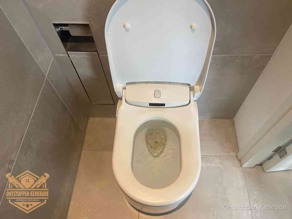 Een wit hangtoilet waarin een prop wc-papier op het water blijft drijven, een duidelijk signaal van een verstopte wc in Kerkrade