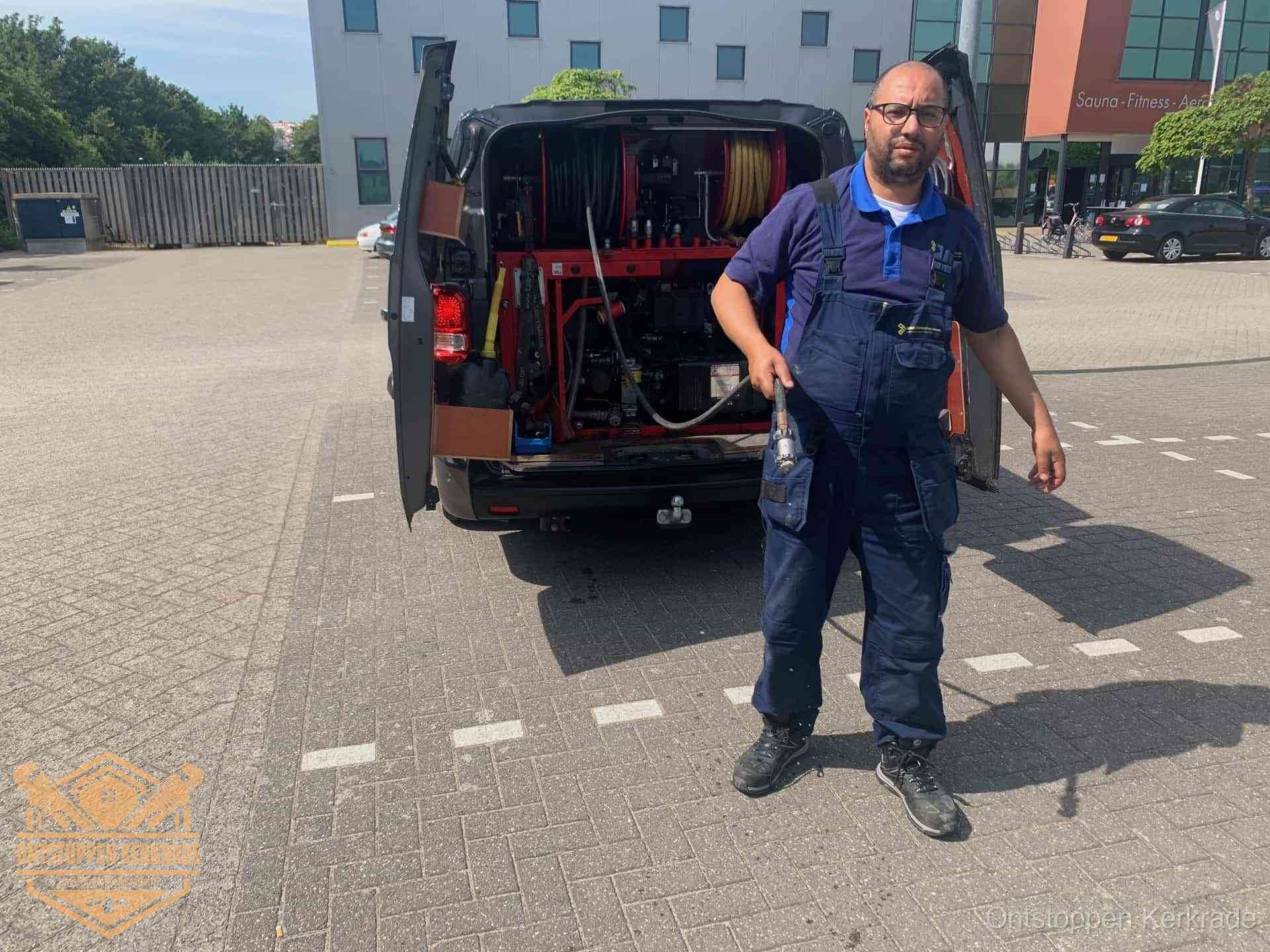 Een monteur bij zijn bestelbus met een hogedruk- en rioolreinigingsunit, klaar om de oorzaak van terugkerende wc-verstoppingen aan te pakken in Kerkrade