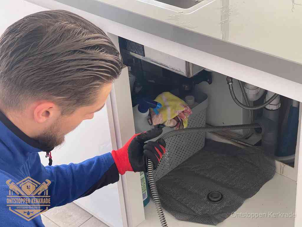 Een monteur voert een flexibele ontstoppingsveer in de afvoer om een verstopping voorbij de bocht van het toilet te bereiken in Kerkrade