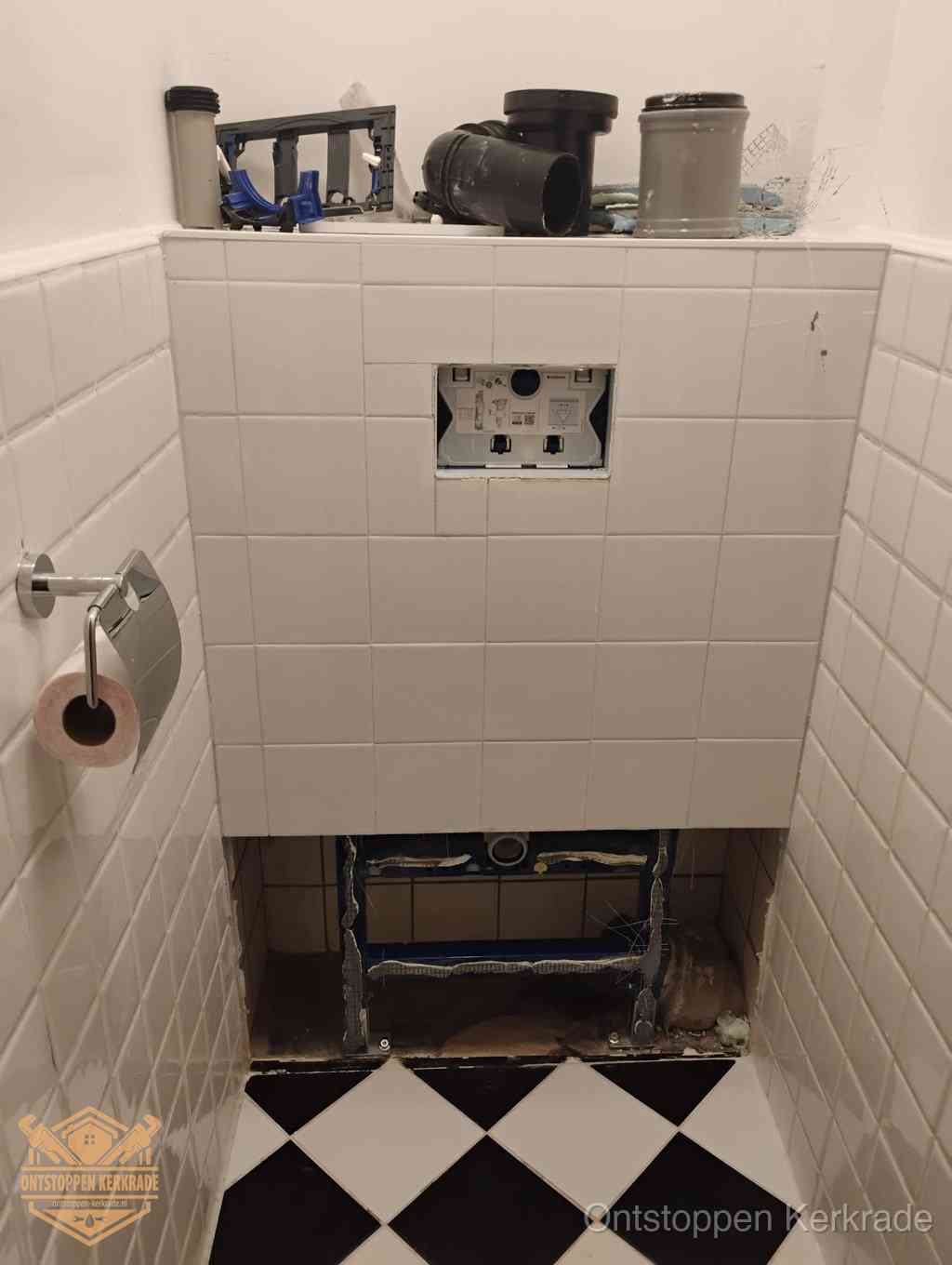 Een toiletruimte waar het hangtoilet en de inbouwreservoir-onderdelen zijn vrijgelegd voor onderhoud, periodiek nazicht voorkomt een wc-verstopping in Kerkrade